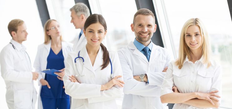 Team of medical professionals looking at camera, smiling, arms crossed