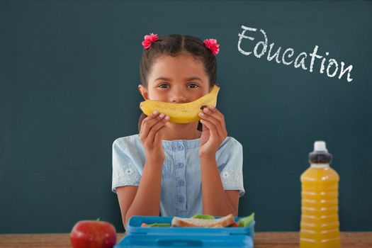 Girl holding banana at table against education text against white background