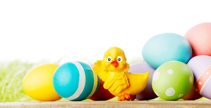 Easter composition with eggs and toy chick on green meadow isolated on white background