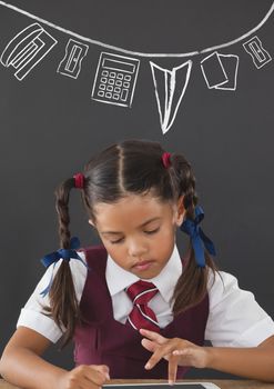 Digital composite of Student girl at table reading against grey blackboard with school and education graphic