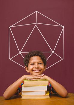 Digital composite of Student boy at table against red blackboard with school and education graphic