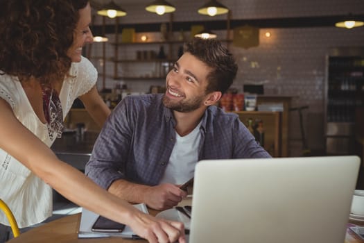 Happy business people looking each other at table in cafe