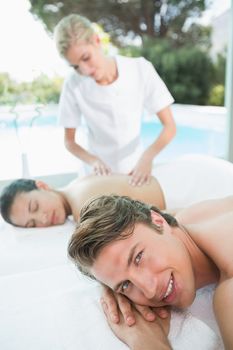 Side view of a young couple enjoying massage at health farm
