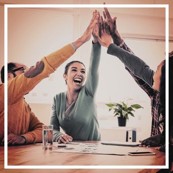 Cheerful business team doing high five while sitting in creative office