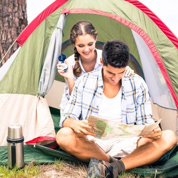 Smiling young couple looking at map outside their tent