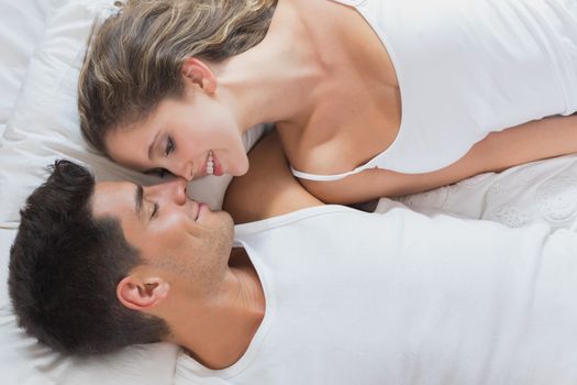 High angle view of romantic young couple lying in bed at home