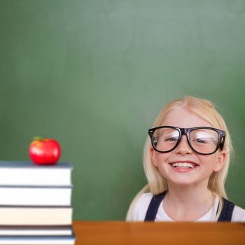 Cute pupil smiling against red apple on pile of books