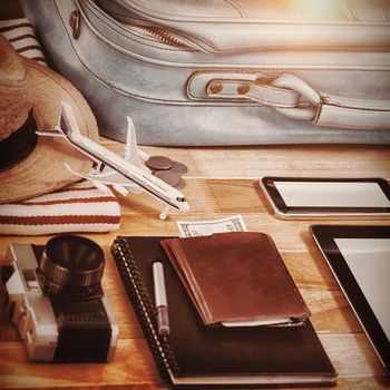 High anlge view of diary with currency by digital tablet and luggage on table