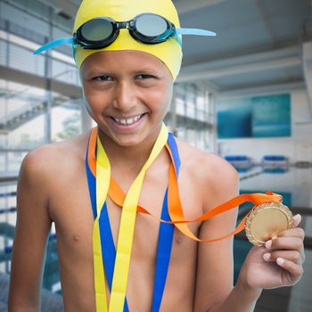 Portrait of smiling boy showing medal against empty swimming pool with large windows