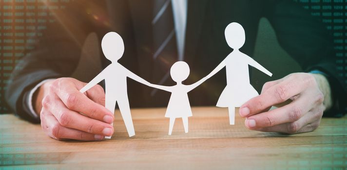 Mid section of businessman holding paper family against blackboard