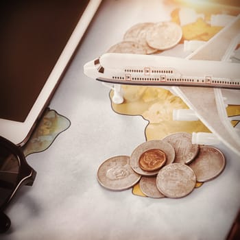 Close up of toy airplane with coins and tablet computer on map