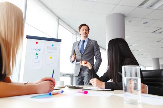 Businessman making financial presentation on flipchart at business meeting