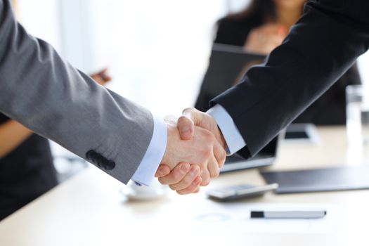 Business handshake at office , working team on background