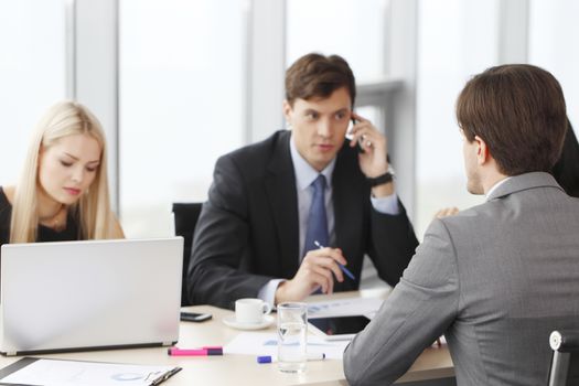 Business partners discussing documents and ideas at meeting in office