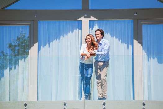 Young couple standing together on balcony of their house