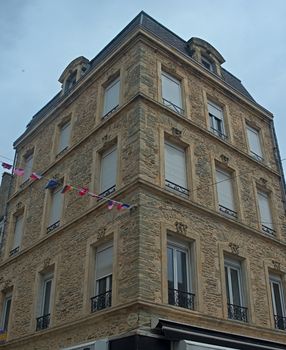 Old traditional French stone corner building with wooden windows