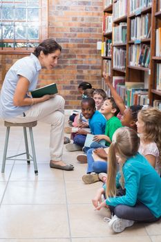 Cute pupils sitting on floor in library at the elementary school