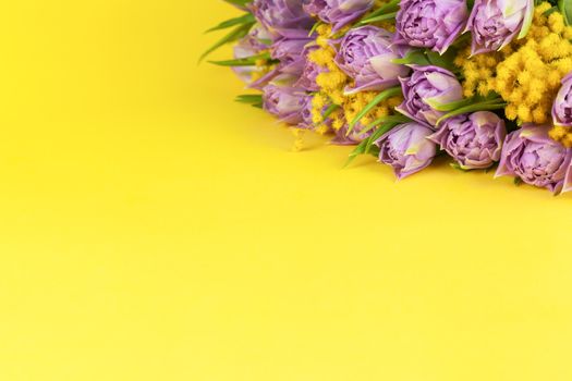 Bouquet of lilac tulips and yellow mimosas on yellow background, copy space, side view, closeup. March 8, February 14, birthday, Valentine's, Mother's, Women's day celebration, spring concept.