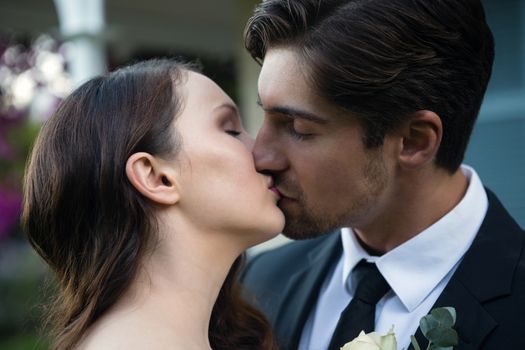 Close up of romantic newlywed couple kissing while standing in park