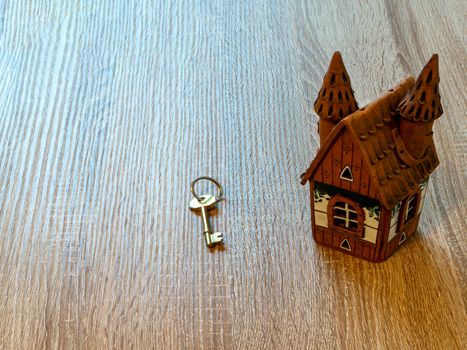 Model of a house and golden key On Wooden Table. Real estate agency, mortgage loan, lottery, buying property.Home loan and investment concept. Copy space