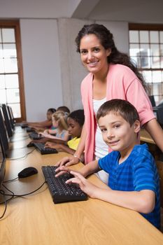 Cute pupils in computer class with teacher at the elementary school