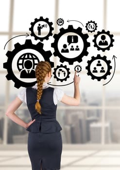 Digital composite of Business woman interacting with people in cogs graphics against office background
