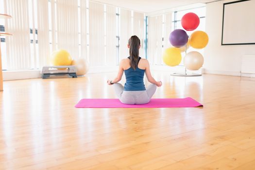 Rear view of woman performing yoga in the gym