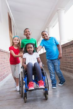 Cute disabled pupil smiling at camera in hall with her friends at the elementary school