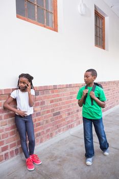 Cute pupil talking on her smartphone in hallway at the elementary school