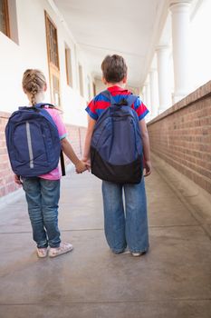 Cute pupils holding hands in corridor at the elementary school