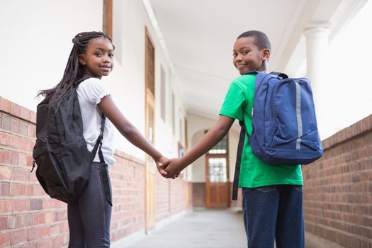 Cute pupils holding hands in corridor at the elementary school