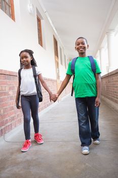 Cute pupils holding hands in corridor at the elementary school