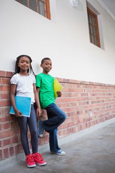 Cute pupils smiling at camera in corridor at the elementary school