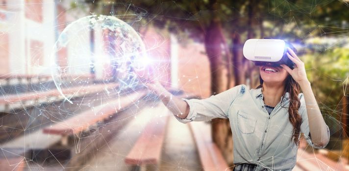Happy young woman gesturing while using virtual reality simulator against global technology background in blue
