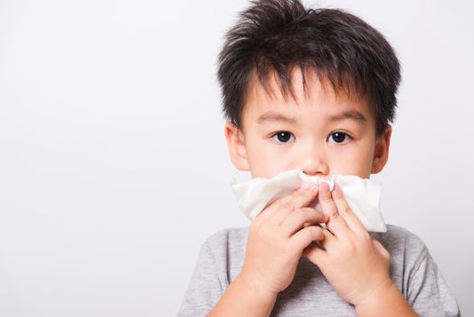 Closeup Asian face, Little children boy cleaning nose with tissue on white background with copy space, health medical care