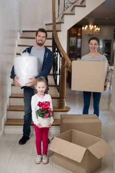 Parents and daughter opening cardboard boxes in living room at home