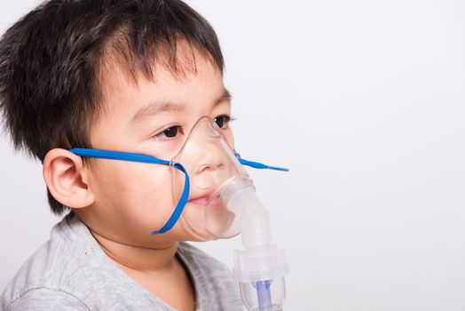 Closeup Asian face, Little children boy sick he using steam inhaler nebulizer mask inhalation oneself on white background, health medical care