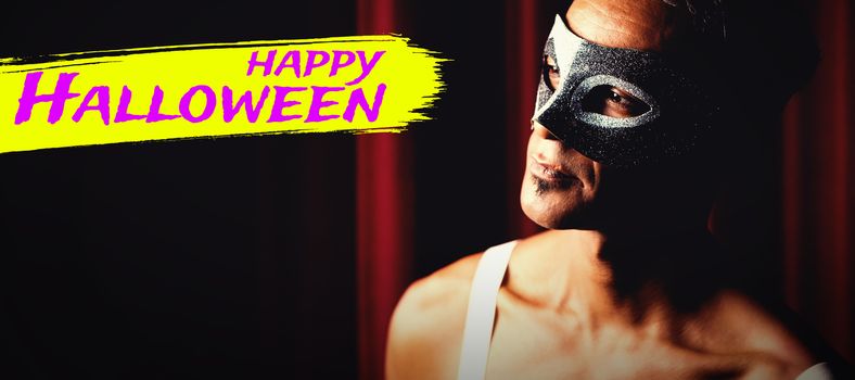 Digital image of happy Halloween text against man in masquerade mask