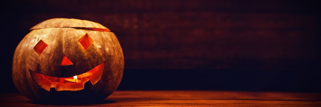 Illuminated jack o lantern on wooden table during Halloween