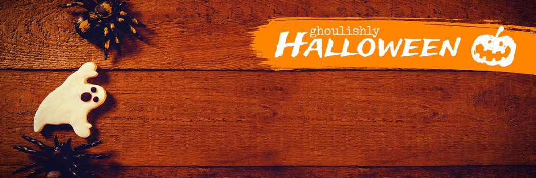 Graphic image of ghoulishly Halloween text against overhead view of decoration with cookie on table