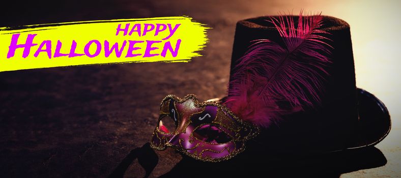 Digital image of happy Halloween text against masquerade masks and hat