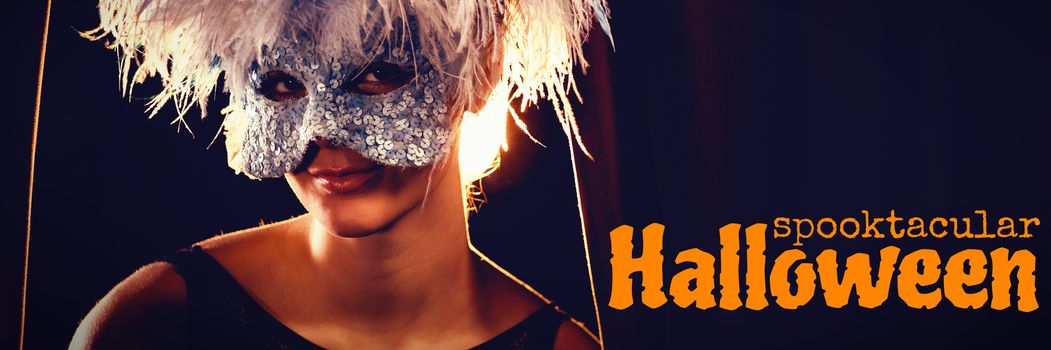 Graphic image of spooktacular Halloween text against portrait of woman in masquerade mask and wig