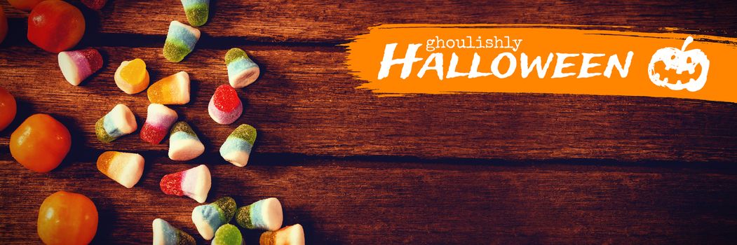 Graphic image of ghoulishly Halloween text against overhead view of colorful sweet food on table