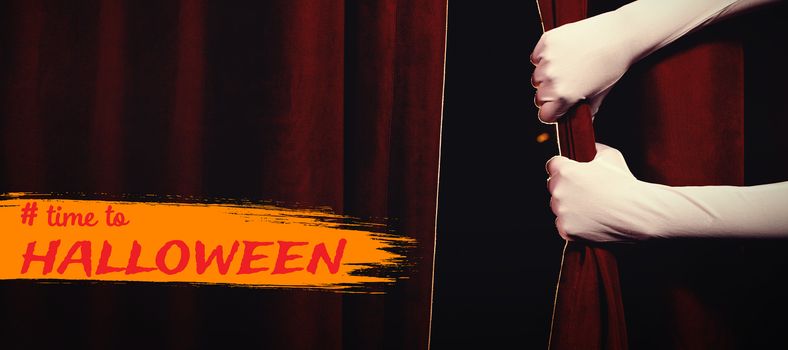 Graphic image of time to Halloween text against cropped hands in gloves holding curtain at stage