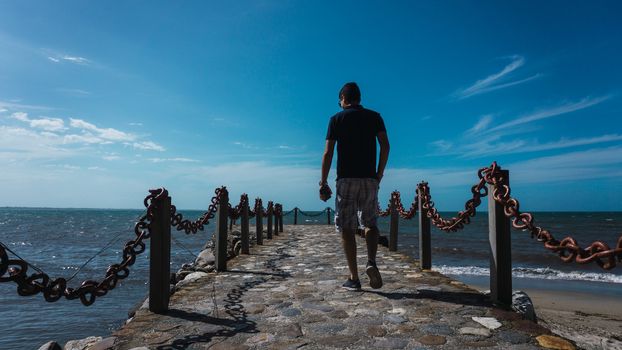 Along man on the pier enjoying the sun and the beautiful of the sea