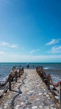 Along man on the pier enjoying the sun and the beautiful of the sea