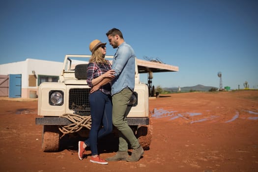 Romantic couple romancing near a car on a sunny day