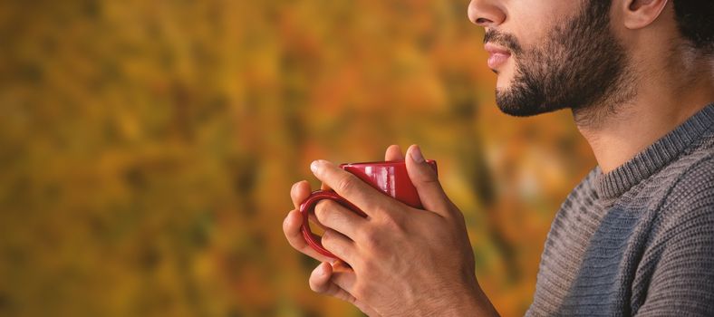 Close-up of thoughtful man having coffee against tree growing outdoors