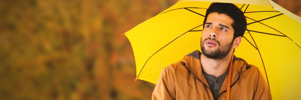 Thoughtful man with yellow umbrella against tree growing outdoors