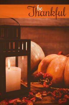 Thanksgiving greeting text against pumpkins and candles on table during halloween